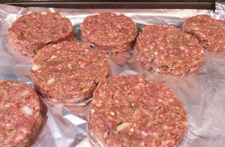 gluten-free burger patties in a single layer on foil