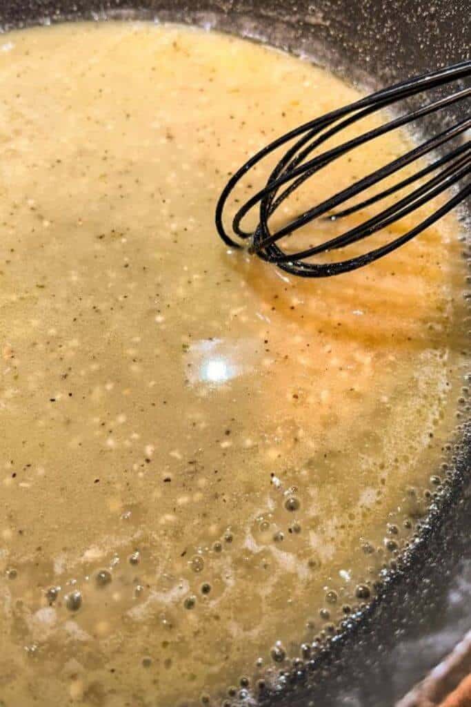 a whisk stirring gluten free lemon garlic sauce