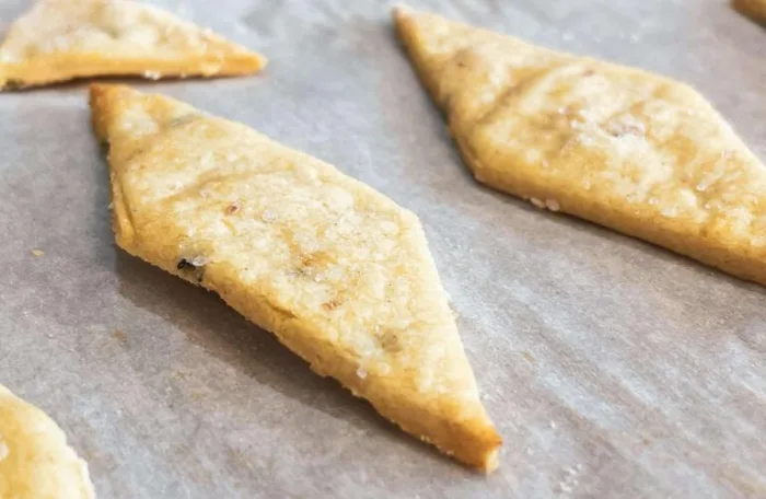 Close-up of gluten-free lemon rosemary sourdough discard crackers on a parchment lined baking sheet