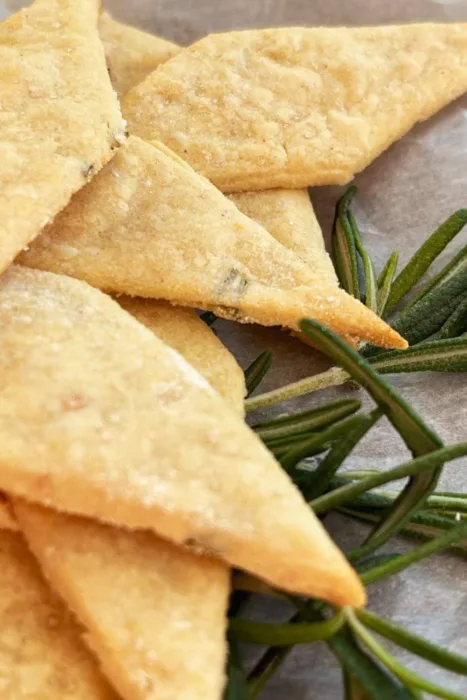 Golden-brown gluten-free lemon rosemary sourdough discard crackers with visible rosemary 