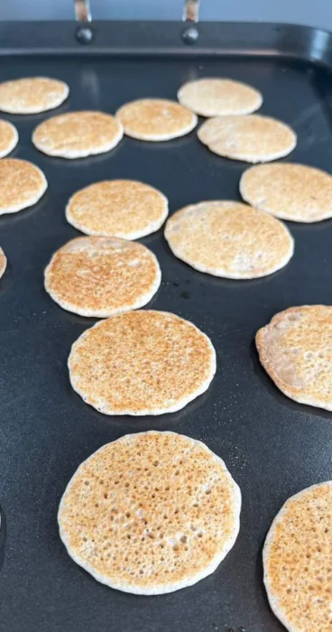 Flipping golden-brown sourdough discard pancakes on a stovetop skillet for even cooking