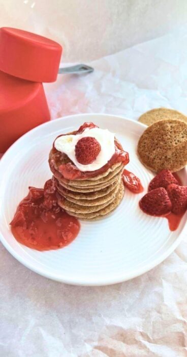 Drizzling strawberry sauce over a stack of warm gluten-free sourdough discard pancakes