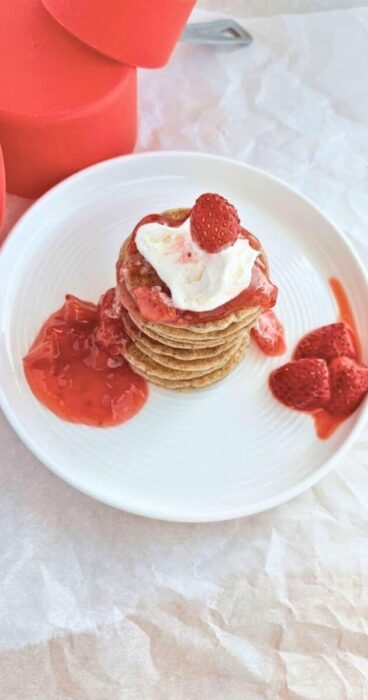 Gluten-free sourdough discard pancakes served with strawberries and strawberry sauce on the side.