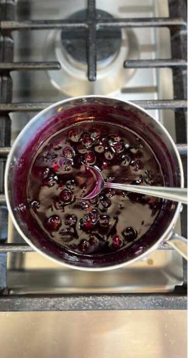 Thick blueberry topping simmering in a pan that's both gluten free and dairy free.