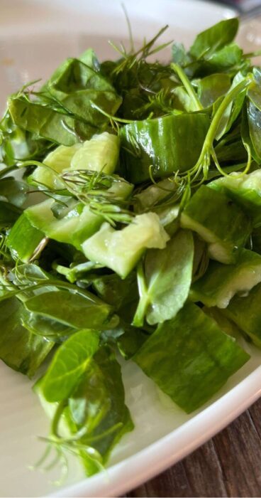 Close-up of smashed cucumbers tossed in a flavorful gluten-free dressing with chopped dill.