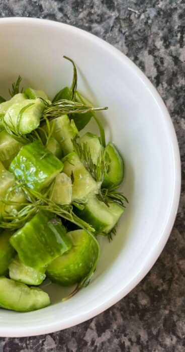 A vibrant bowl filled with smashed cucumbers, fresh dill, and a tangy gluten-free dressing.