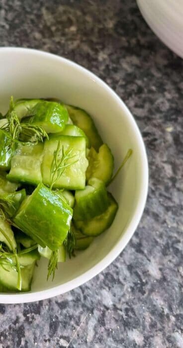 A gluten-free smashed cucumber salad garnished with fragrant dill leaves, appealing to the senses.