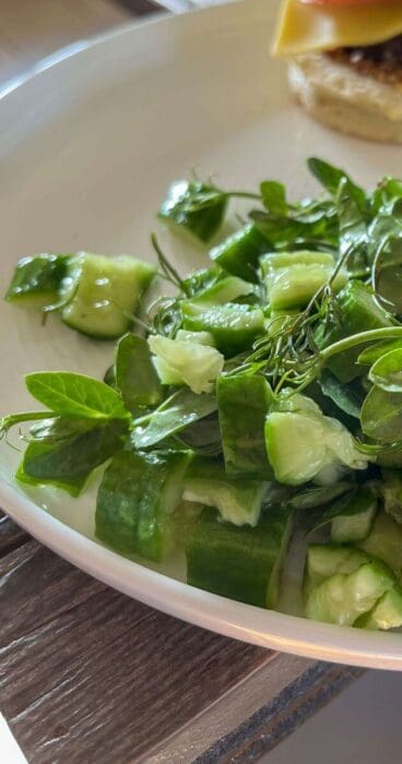 A tantalizing image of smashed cucumbers paired harmoniously with fresh dill and tender pea shoots in a gluten-free salad.