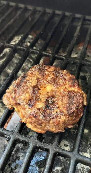 Savory beef bacon burger patty, on the grill, highlighting the bacon within the mixture, gluten-free.