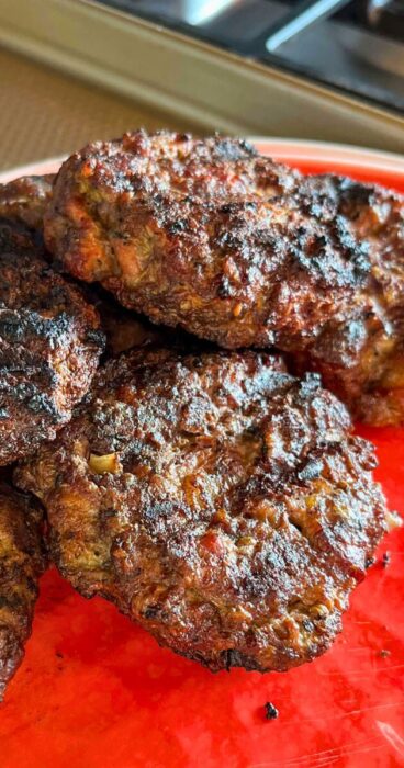 Close-up of a gluten-free beef bacon burger, featuring crispy bacon pieces mixed into the patty, no bun in sight.