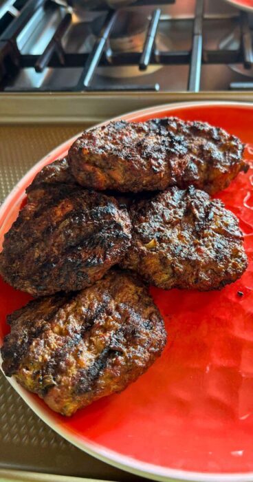 Mouthwatering beef bacon burger patties, mixed with bacon, served on a red plate