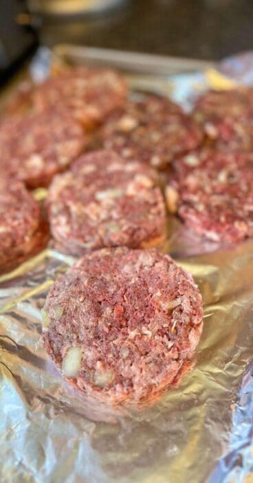 raw gluten-free beef bacon burger patty on a foil-lined baking sheet