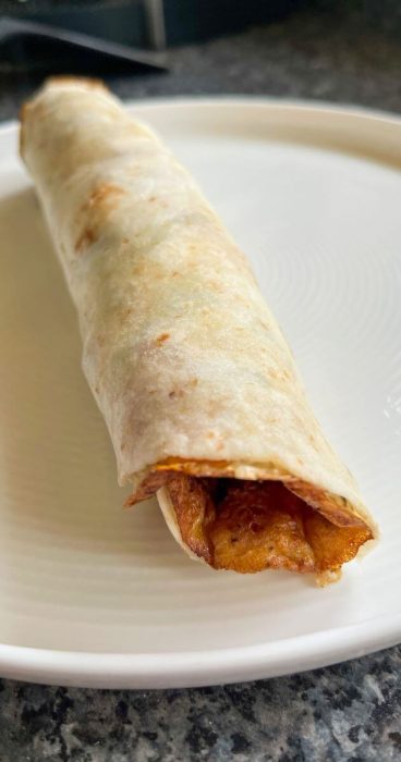 Mouth-watering gluten-free breakfast wrap with an omelet, bacon, and peppers inside a soft tortilla.