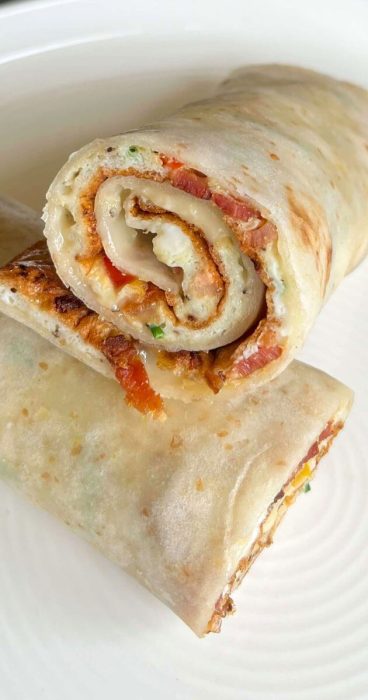 Healthy gluten-free breakfast wrap with a omelet, peppers, bacon, and melted cheese.