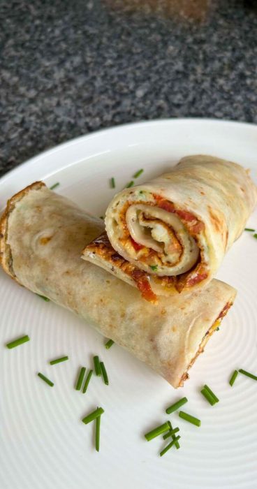 Gluten-free breakfast wrap with a fluffy omelet and fresh vegetables inside a soft tortilla.