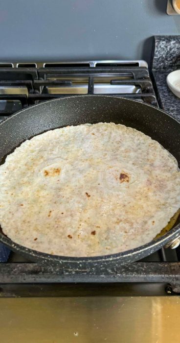 gluten-free tortilla on top of a fluffy omelet in a skillet